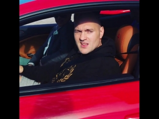 tyson fury drives a red sports car through spain.